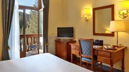 Camera con scrivania, TV e balcone affacciato sui boschi