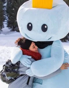 Bambina abbraccia la mascotte dell'hotel sulla neve