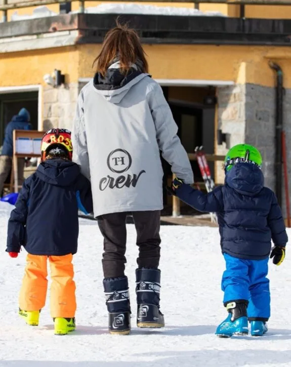 Animatrice con bambini in tenuta da sci diretti alle piste