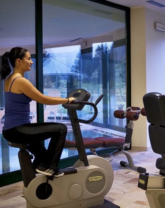 Sala fitness dell'hotel con cyclette e attrezzature vista piscina