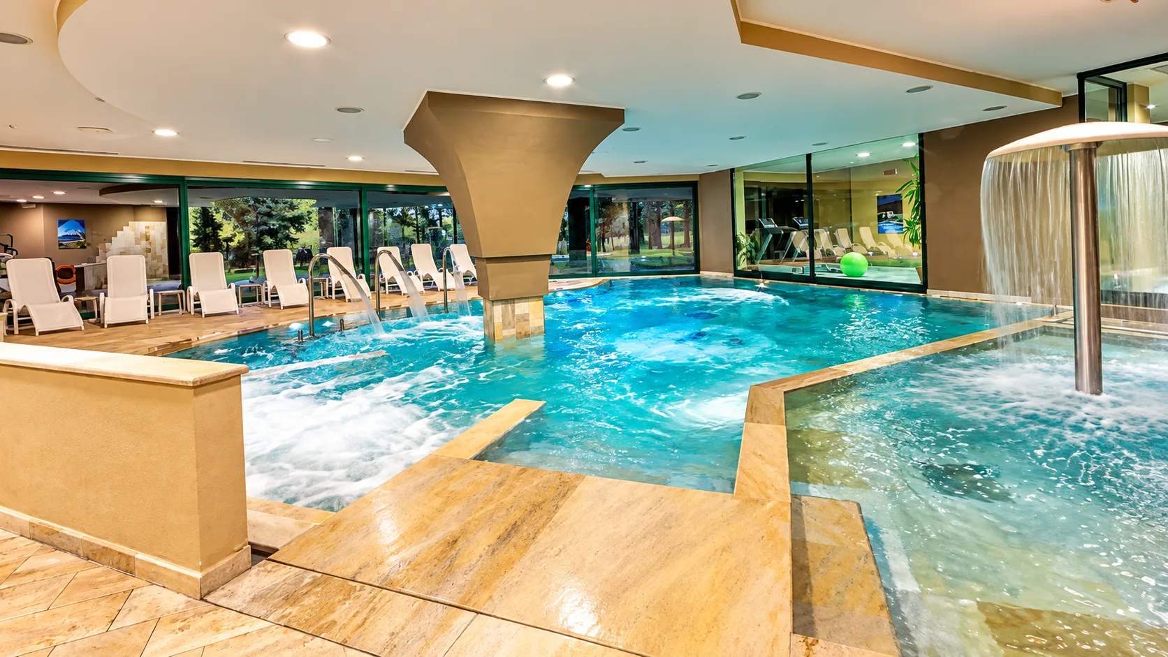 Piscina coperta con idromassaggio e cascate d'acqua nella zona wellness