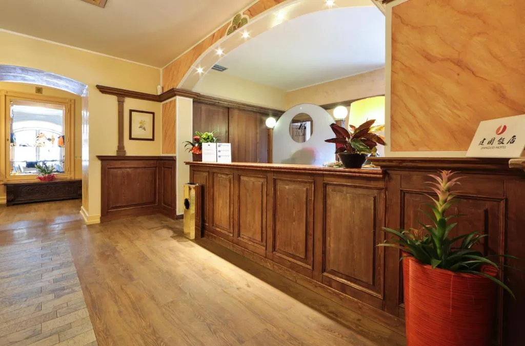 Reception dell'hotel con banco in legno scuro e piante ornamentali
