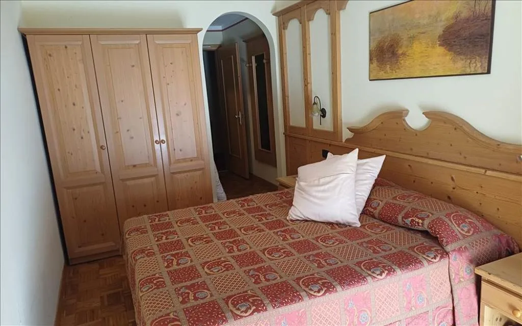 Camera con armadio in legno, letto matrimoniale e copriletto decorato