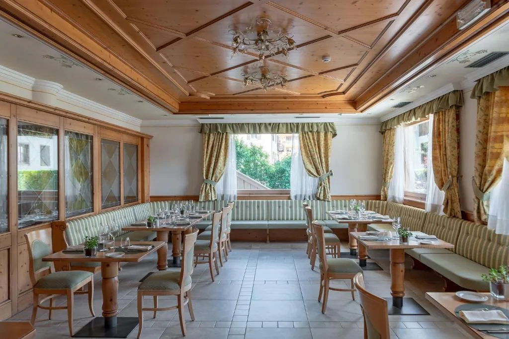 Sala da pranzo con divanetti verdi e tavoli apparecchiati