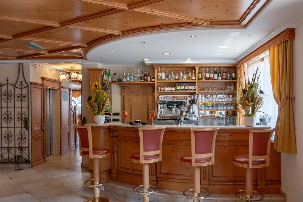 Bar interno con bancone curvo in legno e sgabelli rossi
