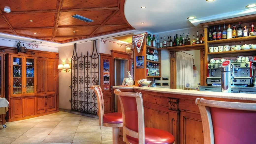 Bar dell'hotel con bancone in legno e sgabelli rossi