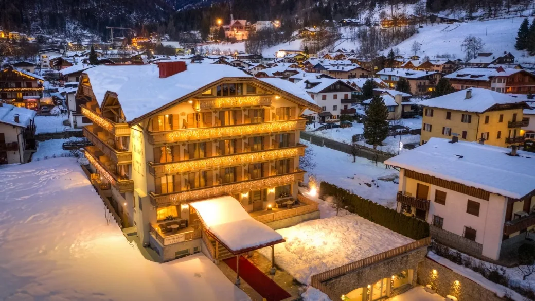 Veduta aerea serale dell'hotel illuminato tra le case innevate del paese