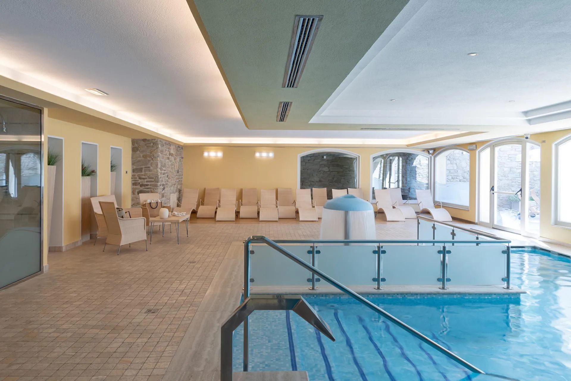 Area piscina interna con lettini relax e fontana centrale