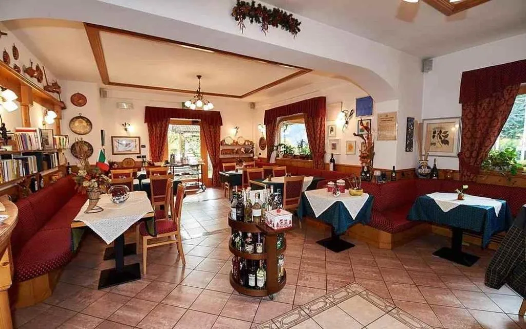 Sala ristorante interna con tavoli, panche rosse e arredamento tradizionale alpino