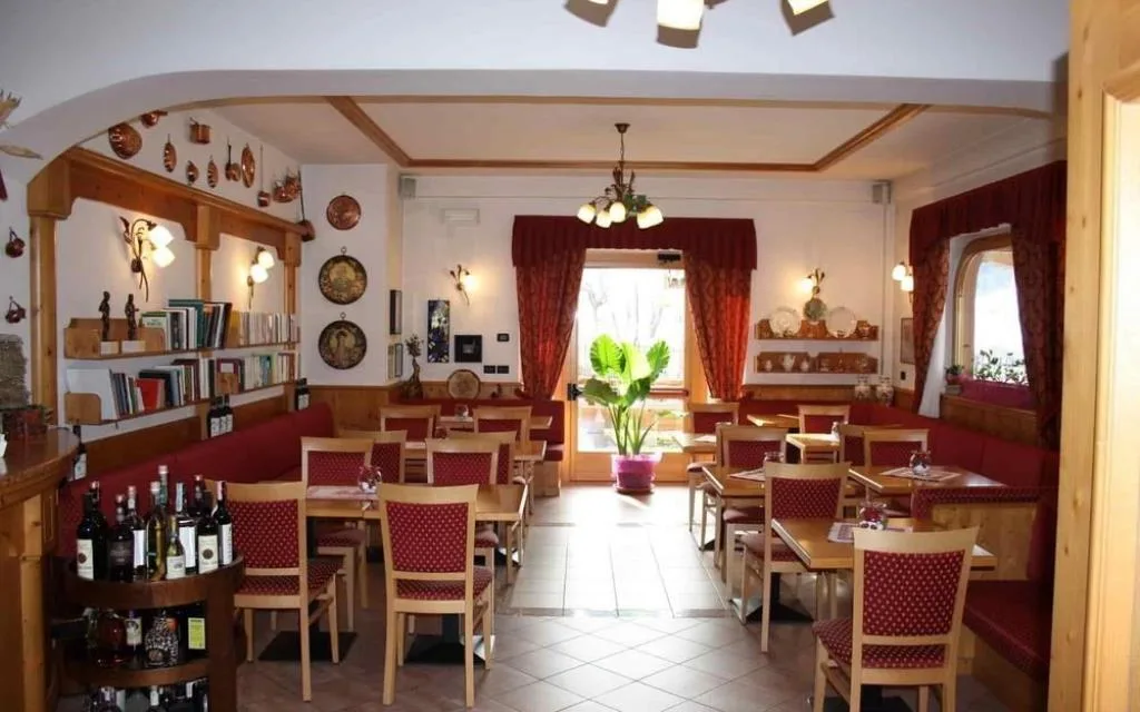 Sala ristorante interna con tavoli, panche rosse e arredi tradizionali