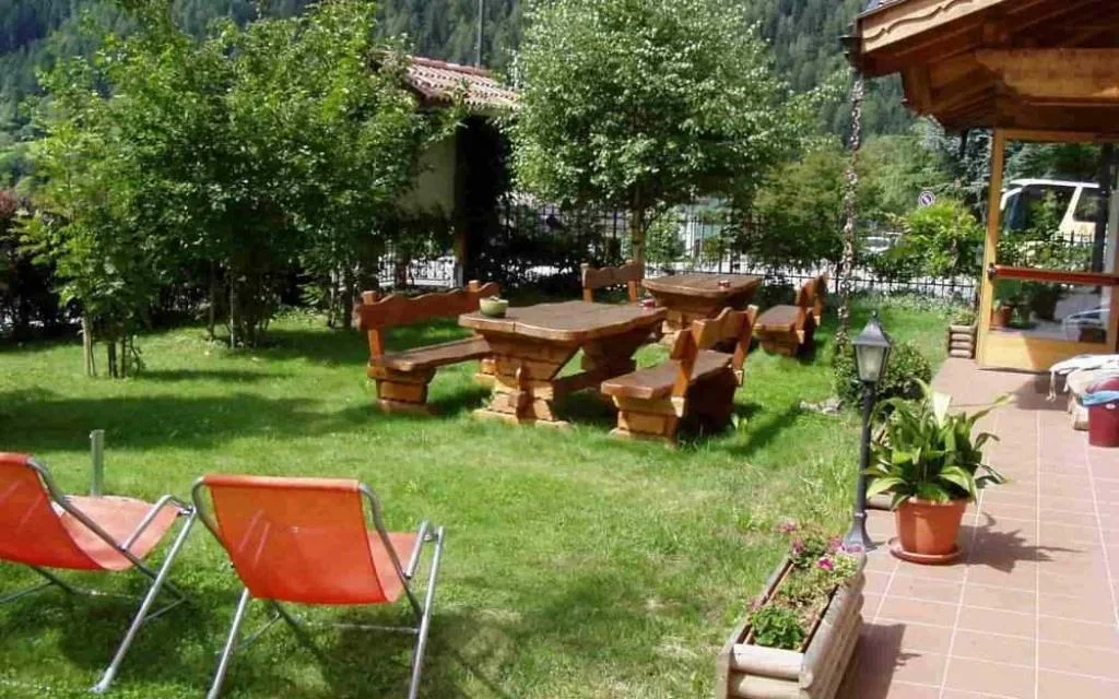 Giardino esterno con tavoli e panche in legno, sdraio arancioni e terrazza