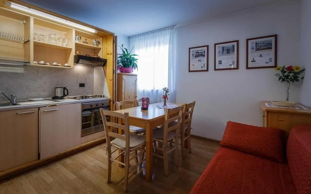 Cucina attrezzata di un appartamento con tavolo da pranzo e divano rosso