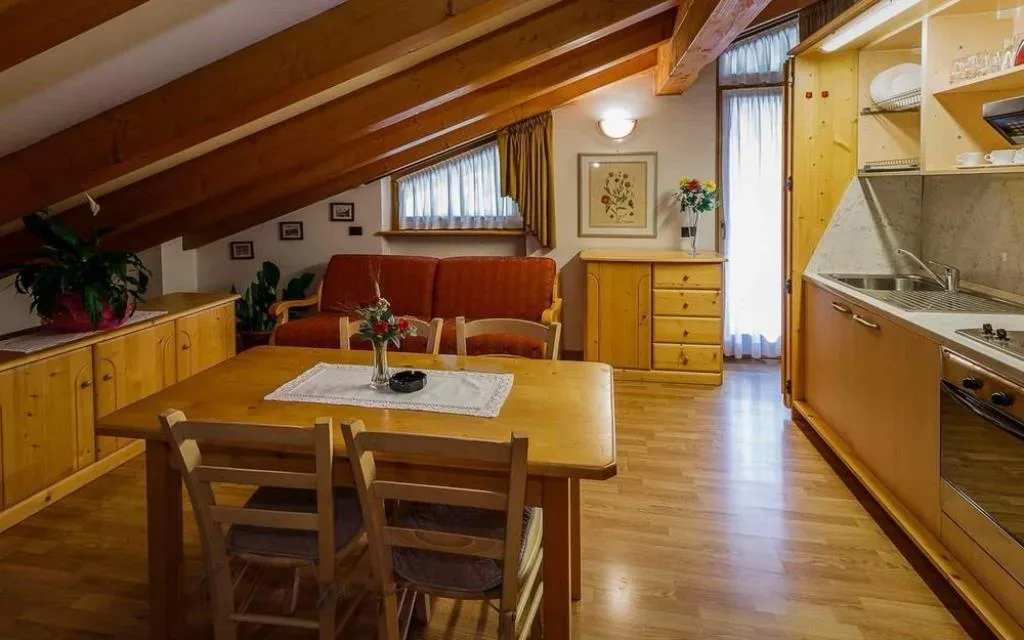 Soggiorno mansardato con travi in legno, angolo cottura e tavolo da pranzo