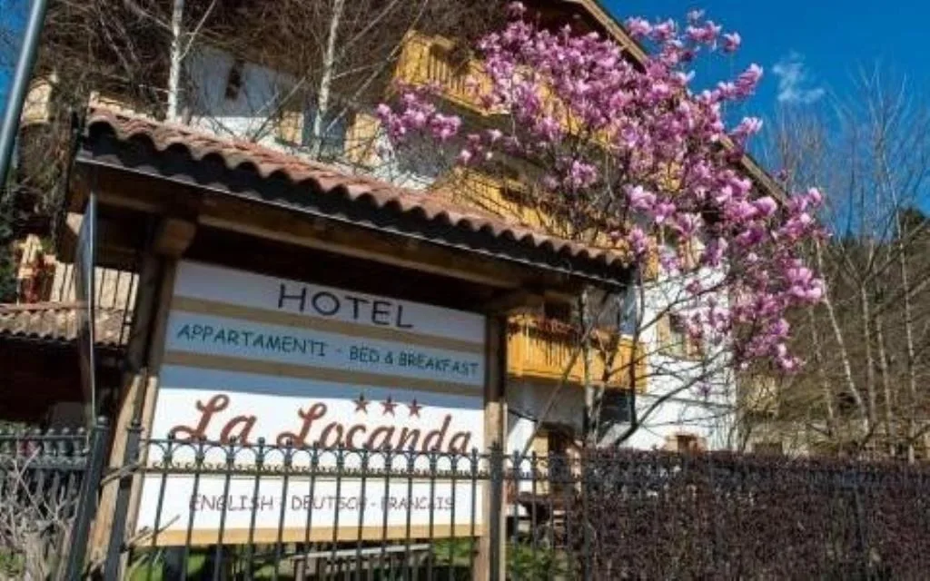 Insegna in legno dell'Hotel La Locanda con albero di magnolia in fiore