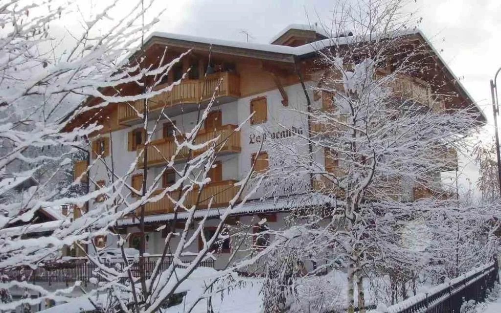 Hotel La Locanda innevato visto tra alberi coperti di neve